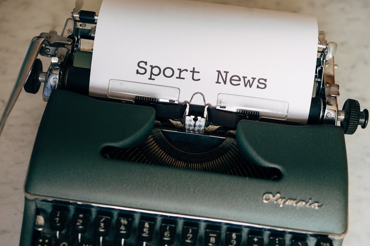 Close-up of a vintage typewriter with a paper showing 'Sport News', evoking nostalgia and classic journalism.